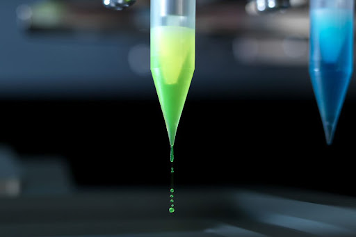 High Throughput Design of Experiments: a liquid dispesning tip uses positive displacement to shoot tiny beads of water towards a well below